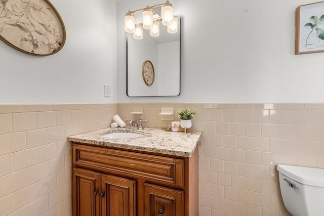 bathroom featuring toilet, vanity, and tile walls