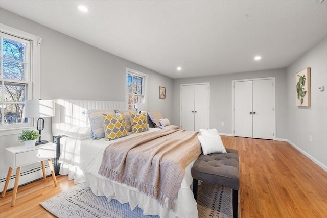 bedroom featuring a baseboard heating unit and light wood-type flooring