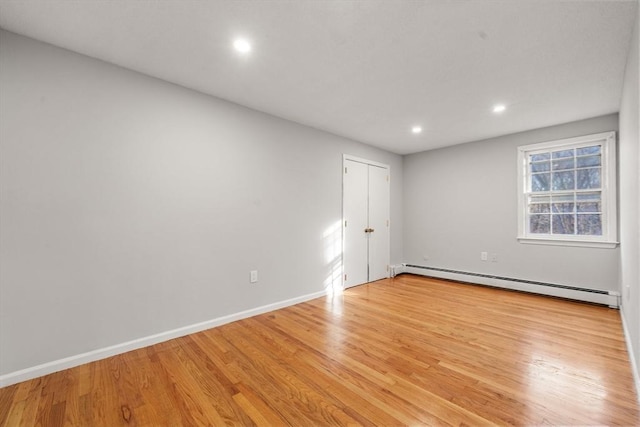 empty room with light hardwood / wood-style floors and baseboard heating