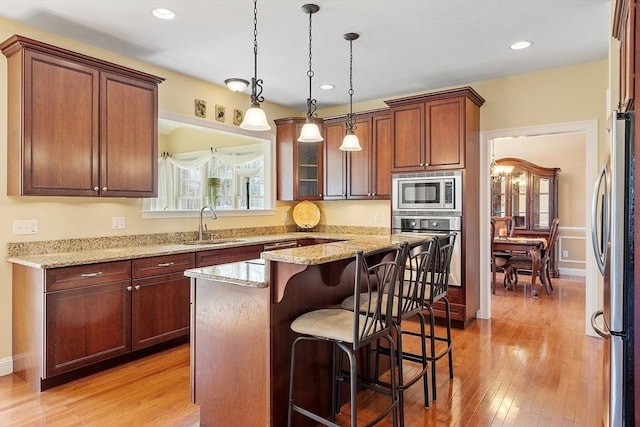 2 Rich Rd, Milford, MA 01757 - kitchen featuring appliances with stainless steel finishes, light stone counters, a sink, a kitchen breakfast bar, and a kitchen island