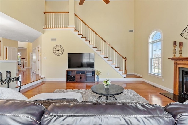 2 Rich Rd, Milford, MA 01757 - living area with stairs, a glass covered fireplace, wood finished floors, ceiling fan, and a high ceiling