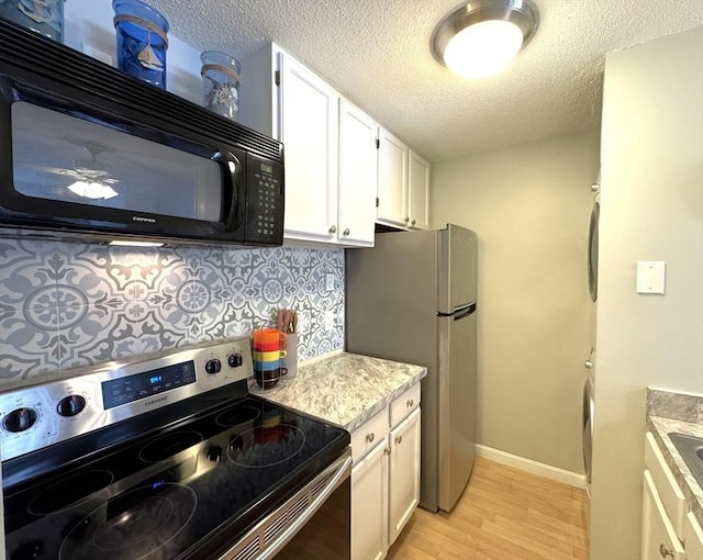 kitchen featuring a textured ceiling, white cabinets, appliances with stainless steel finishes, decorative backsplash, and light hardwood / wood-style flooring