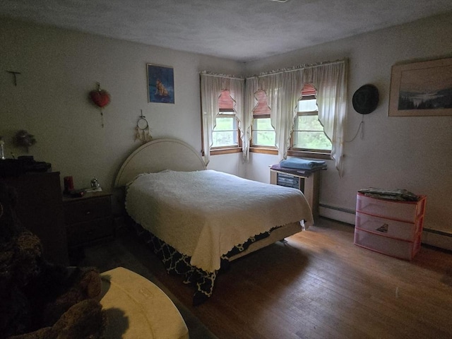 bedroom featuring wood finished floors and a baseboard heating unit
