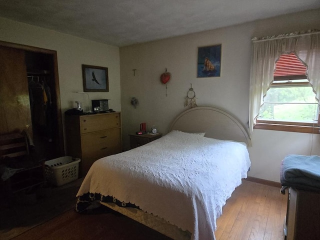 bedroom with hardwood / wood-style flooring, a closet, and baseboards