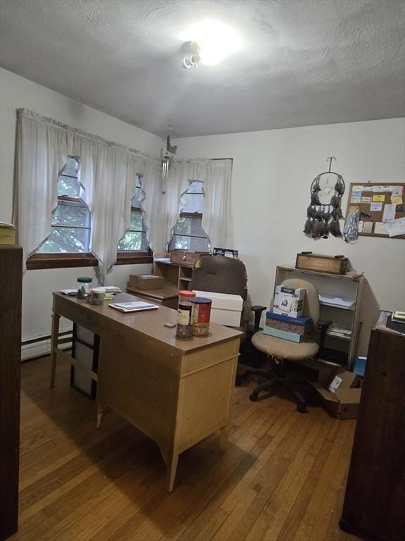 home office with hardwood / wood-style floors and baseboard heating