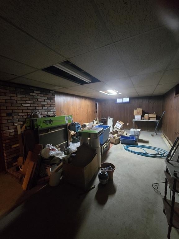 finished below grade area featuring a paneled ceiling, carpet flooring, and wooden walls