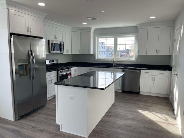 kitchen featuring white cabinetry, a center island, stainless steel appliances, and wood-type flooring