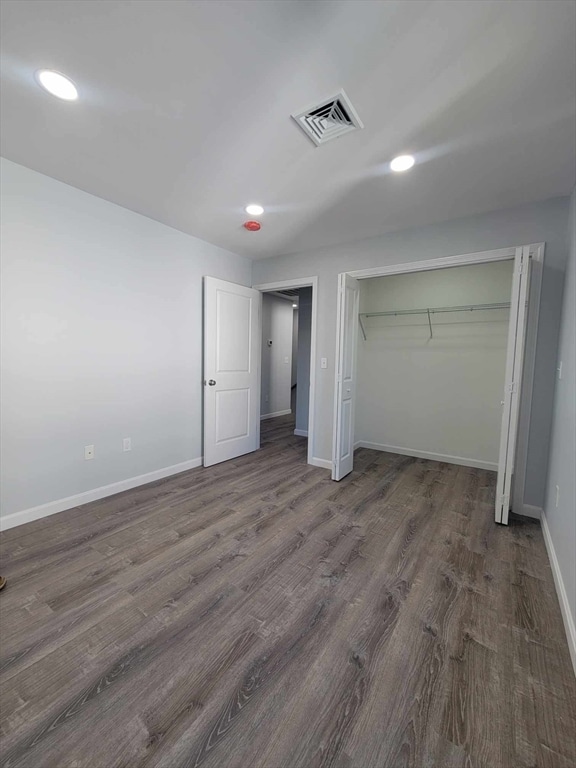 unfurnished bedroom featuring a closet and dark wood-type flooring