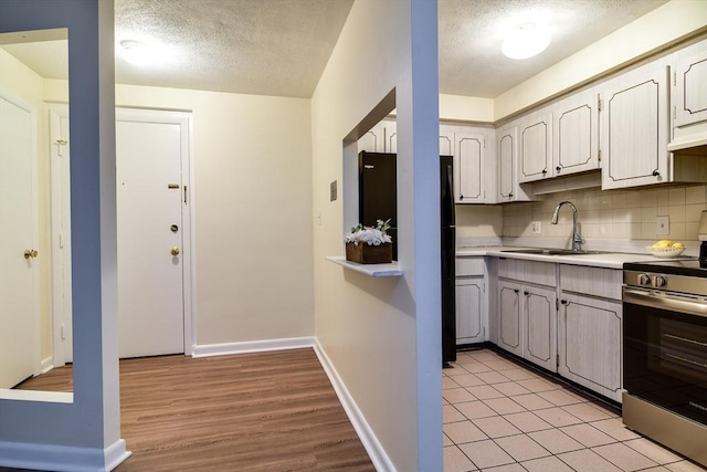915 Edgell Rd Unit 85, Framingham, MA 01701 - kitchen featuring stainless steel range oven, a textured ceiling, light countertops, light wood-style flooring, and backsplash