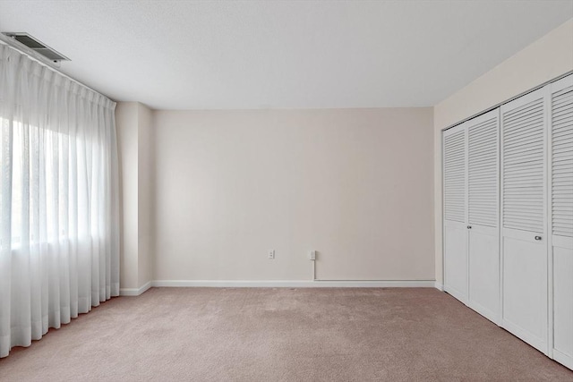 unfurnished bedroom with a closet and light colored carpet