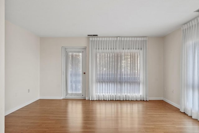 spare room with plenty of natural light and light hardwood / wood-style flooring