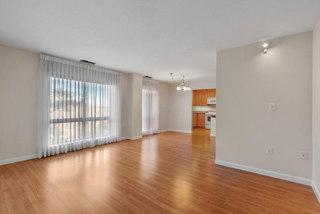 unfurnished living room with light wood-type flooring and an inviting chandelier