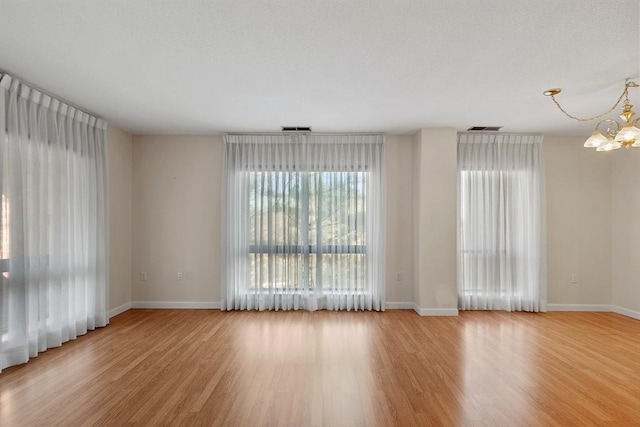 unfurnished room featuring light hardwood / wood-style flooring and an inviting chandelier