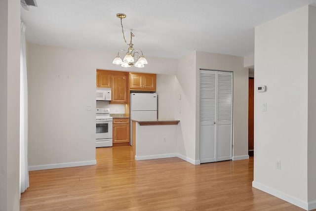 kitchen with light hardwood / wood-style flooring, decorative light fixtures, white appliances, and an inviting chandelier