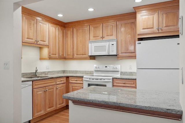 kitchen featuring light stone countertops, light wood-type flooring, white appliances, and sink