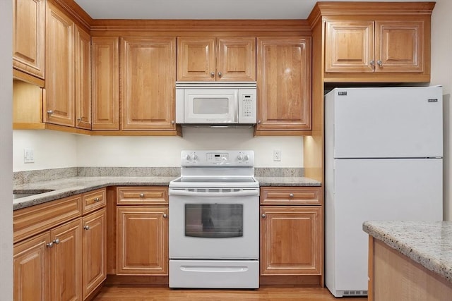 kitchen featuring light stone countertops and white appliances