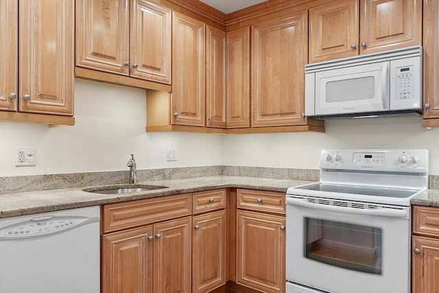 kitchen with white appliances, light stone counters, and sink