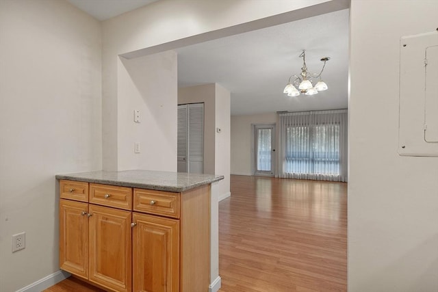 kitchen with light stone countertops, decorative light fixtures, light hardwood / wood-style flooring, and a notable chandelier