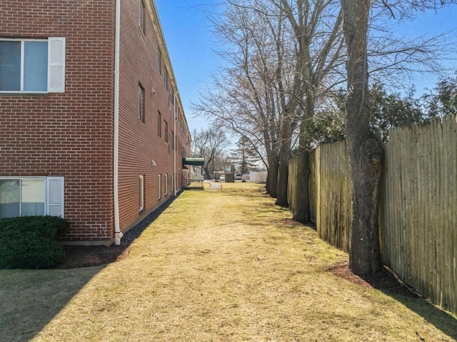 view of home's exterior featuring brick siding, a yard, and fence