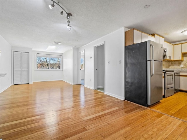 unfurnished living room featuring visible vents, track lighting, baseboards, light wood-type flooring, and a textured ceiling