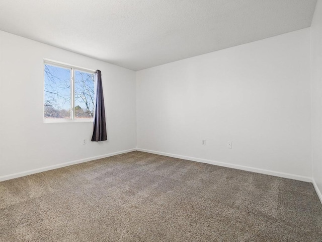 carpeted empty room featuring baseboards and a textured ceiling