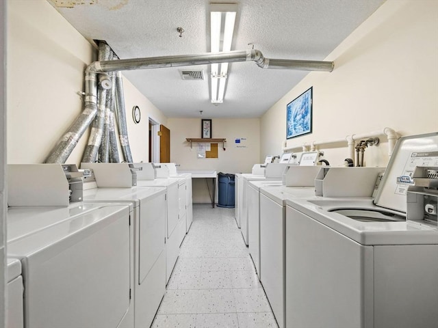 common laundry area featuring visible vents, a textured ceiling, light floors, and washing machine and dryer