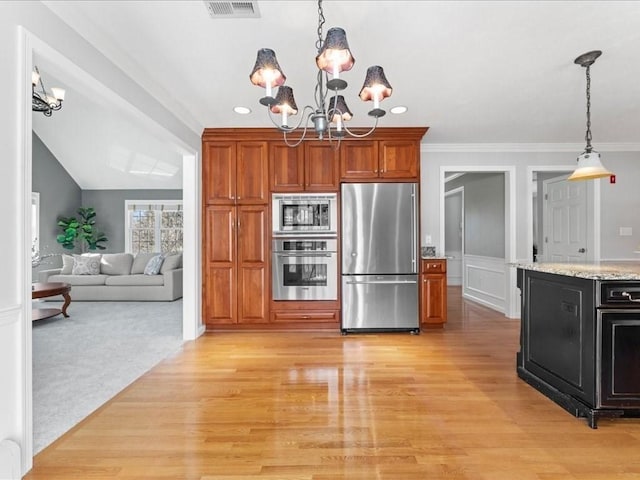 kitchen with light stone counters, a chandelier, light wood-type flooring, appliances with stainless steel finishes, and pendant lighting