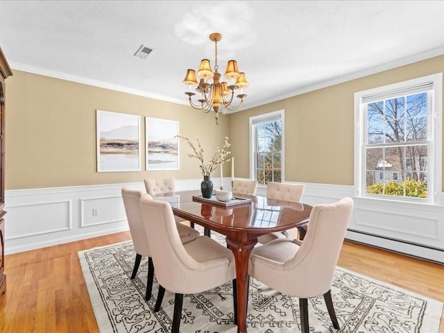 dining space featuring a notable chandelier, a wealth of natural light, ornamental molding, and light wood-type flooring