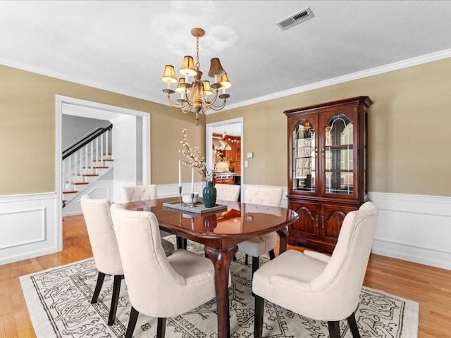 dining space featuring a notable chandelier, crown molding, and light hardwood / wood-style flooring