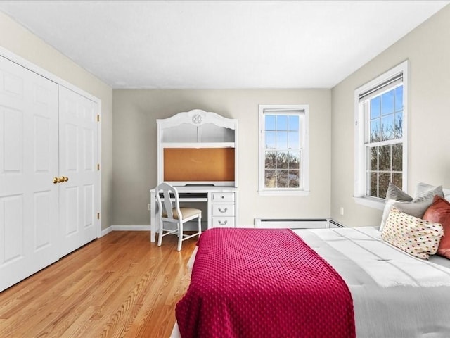 bedroom featuring light hardwood / wood-style floors, a closet, and a baseboard heating unit