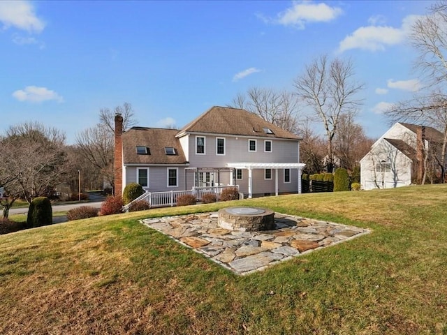 back of property with a fire pit and a lawn