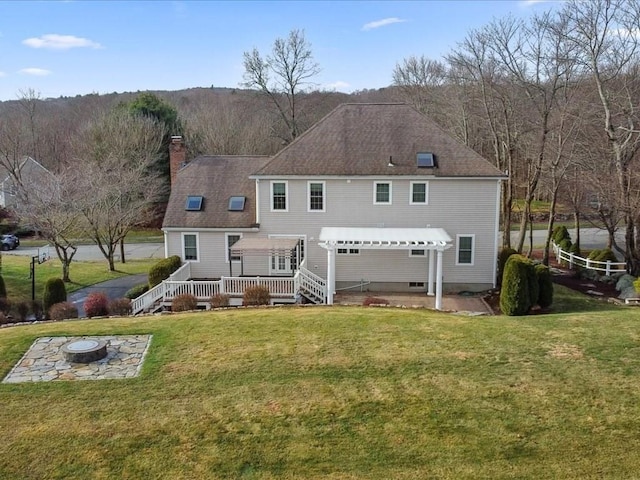 rear view of property featuring a yard, a pergola, a deck, and a fire pit