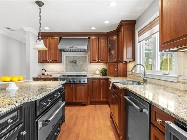 kitchen with stainless steel appliances, sink, light stone counters, and wall chimney exhaust hood