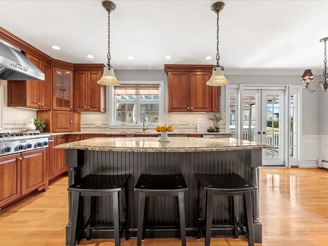 kitchen with light stone counters, hanging light fixtures, a breakfast bar, and a kitchen island