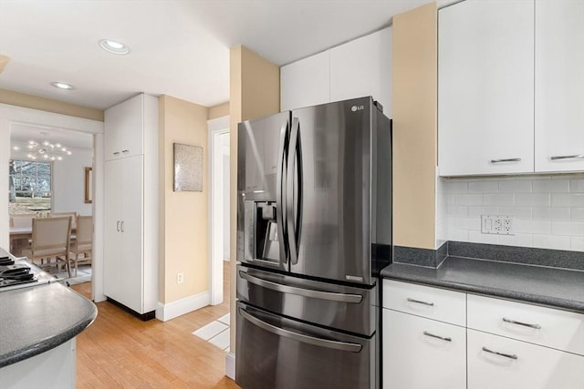 kitchen with light wood-style floors, dark countertops, backsplash, and stainless steel fridge with ice dispenser