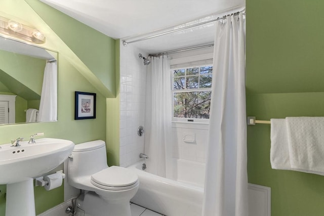 bathroom featuring a sink, shower / bathtub combination with curtain, and toilet