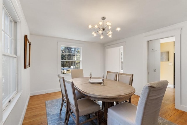 dining area featuring baseboards, light wood-type flooring, and an inviting chandelier