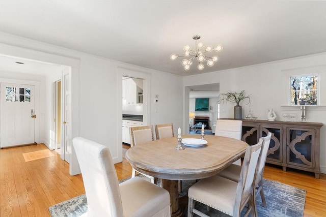 dining space with light wood-style floors, a chandelier, and a fireplace