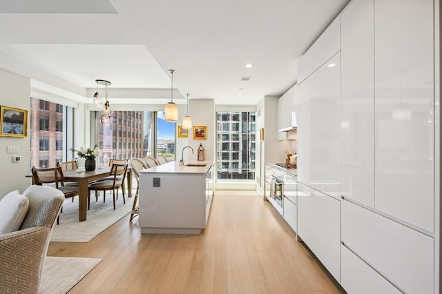 133 Seaport Blvd Unit 823, Boston, MA 02210 - kitchen with a sink, modern cabinets, white cabinets, light wood-type flooring, and recessed lighting