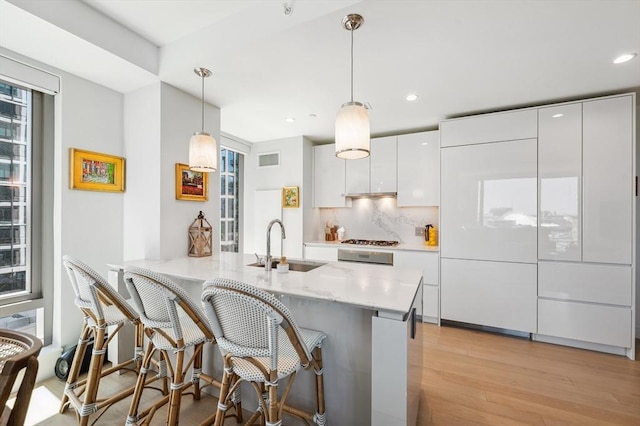 133 Seaport Blvd Unit 823, Boston, MA 02210 - kitchen featuring a sink, light wood-type flooring, white cabinets, a kitchen bar, and recessed lighting