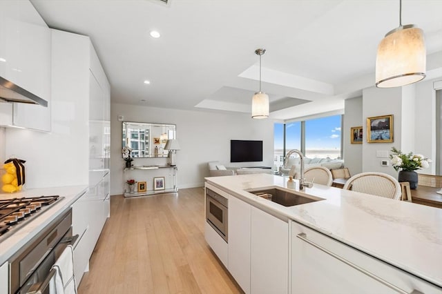 133 Seaport Blvd Unit 823, Boston, MA 02210 - kitchen with a sink, light wood-style flooring, white cabinetry, stainless steel gas stovetop, and pendant lighting