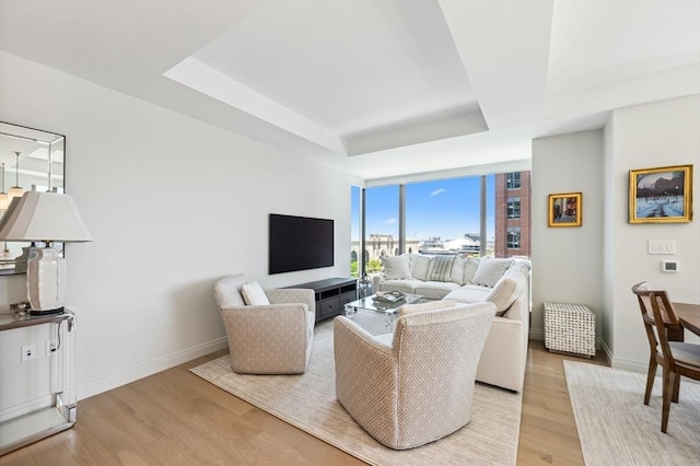 133 Seaport Blvd Unit 823, Boston, MA 02210 - living area with a raised ceiling, light wood finished floors, baseboards, and a wall of windows