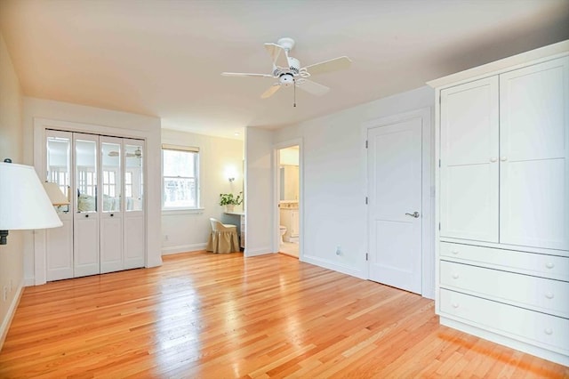 interior space featuring baseboards, a ceiling fan, light wood-type flooring, and ensuite bath