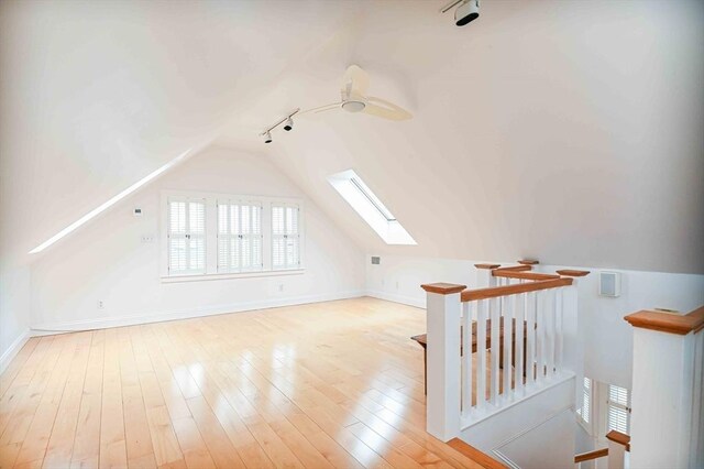 additional living space with vaulted ceiling with skylight, baseboards, and hardwood / wood-style floors