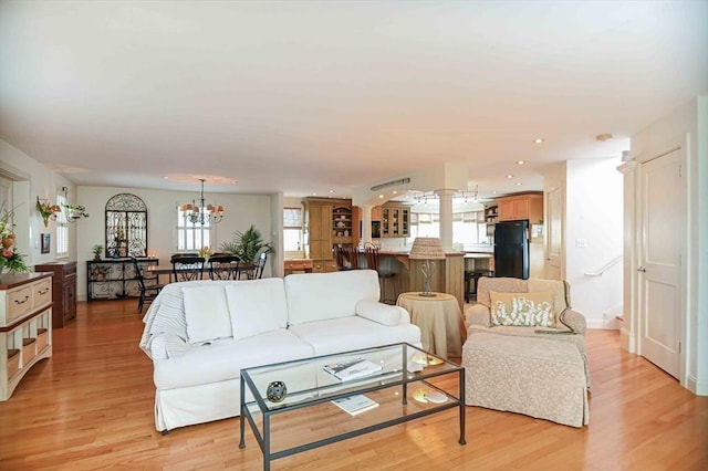 living area featuring recessed lighting, light wood-style flooring, and a chandelier