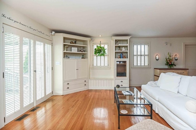 living room with visible vents, light wood-style floors, and baseboards