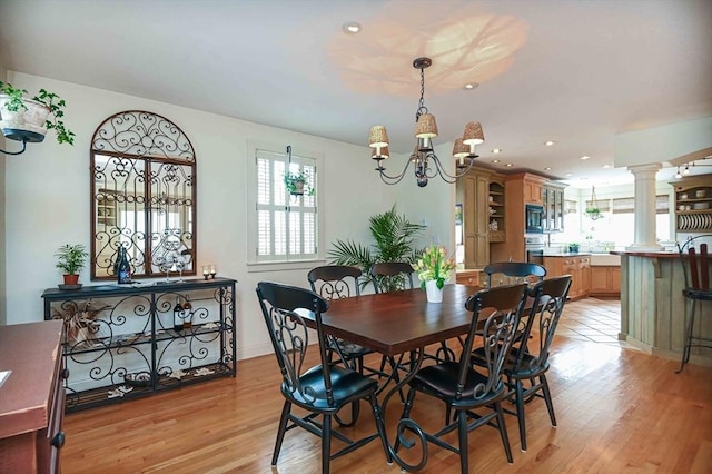 dining area featuring plenty of natural light, light wood-style flooring, and a notable chandelier