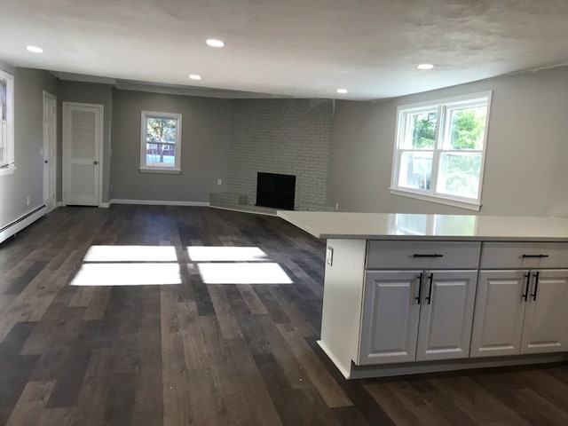 kitchen with white cabinetry, a fireplace, baseboard heating, and dark wood-type flooring