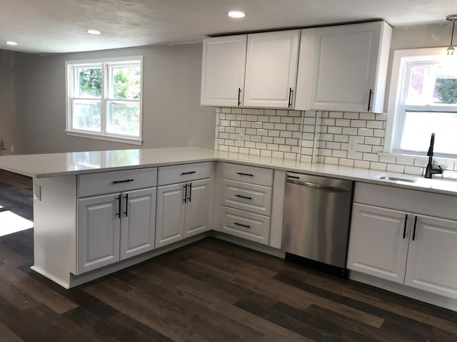 kitchen featuring dark wood-type flooring, dishwasher, kitchen peninsula, backsplash, and white cabinetry