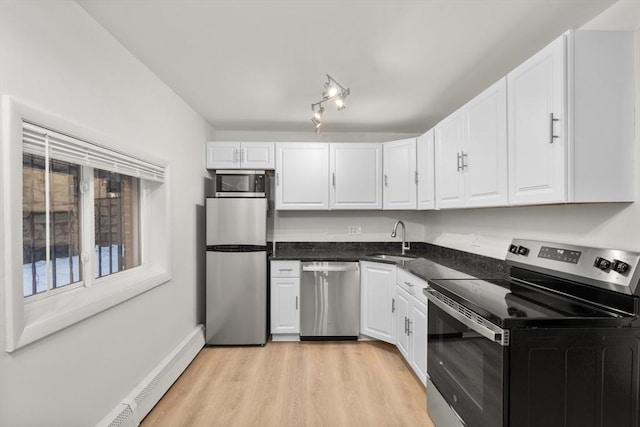 kitchen with appliances with stainless steel finishes, a baseboard heating unit, sink, light hardwood / wood-style flooring, and white cabinetry